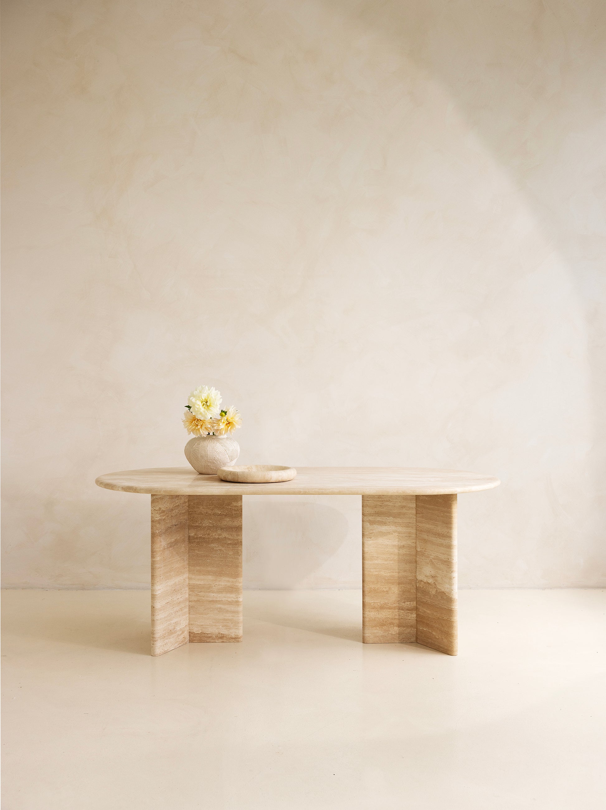 A rectangular dining table with curved edges, made of light-colored wood, displayed against a neutral background.