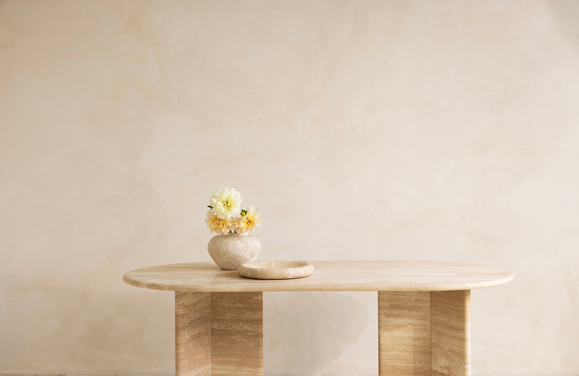 A rectangular dining table with curved edges, made of light-colored wood, displayed against a neutral background.