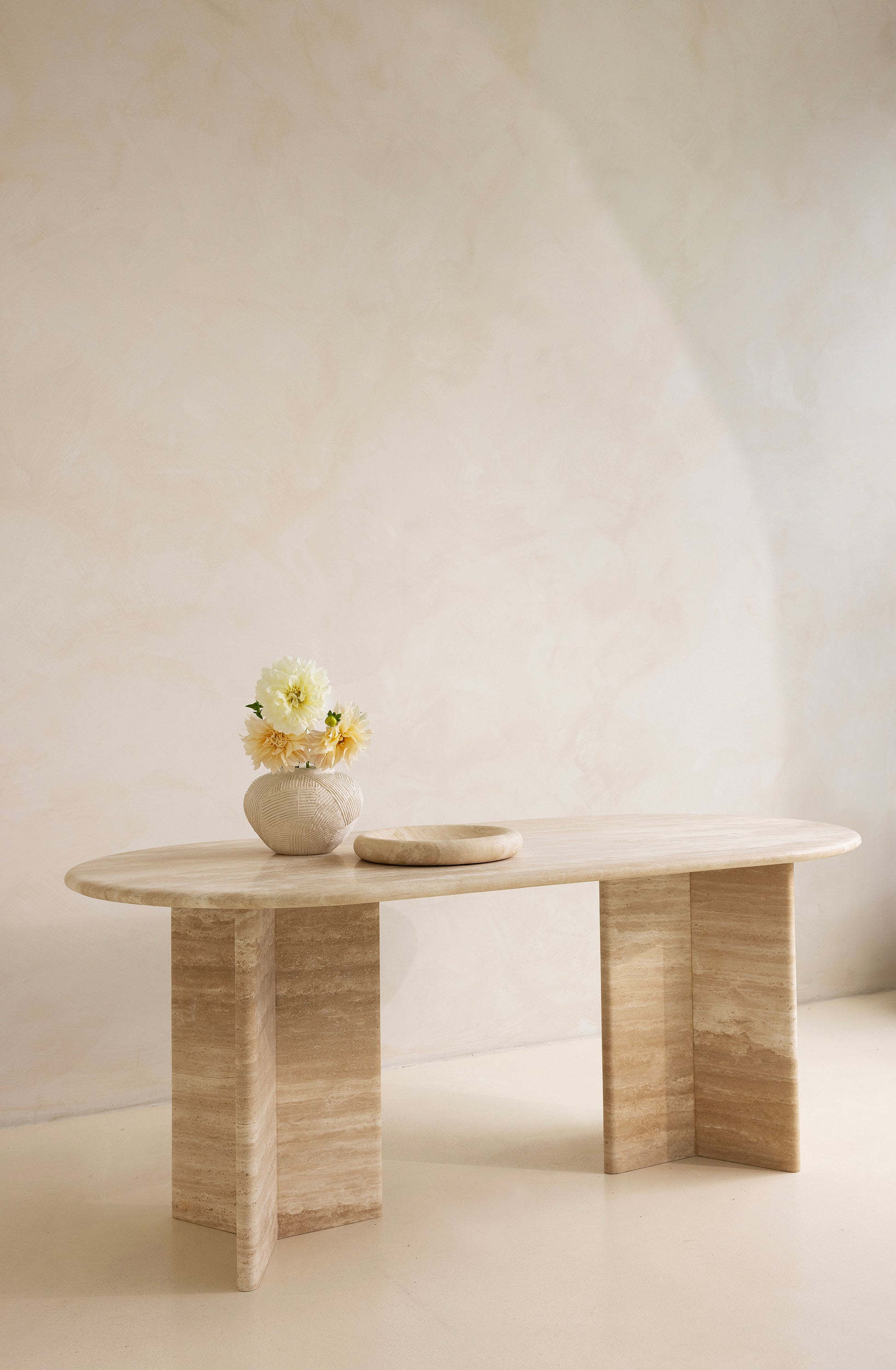 A rectangular dining table with curved edges, made of light-colored wood, displayed against a neutral background.