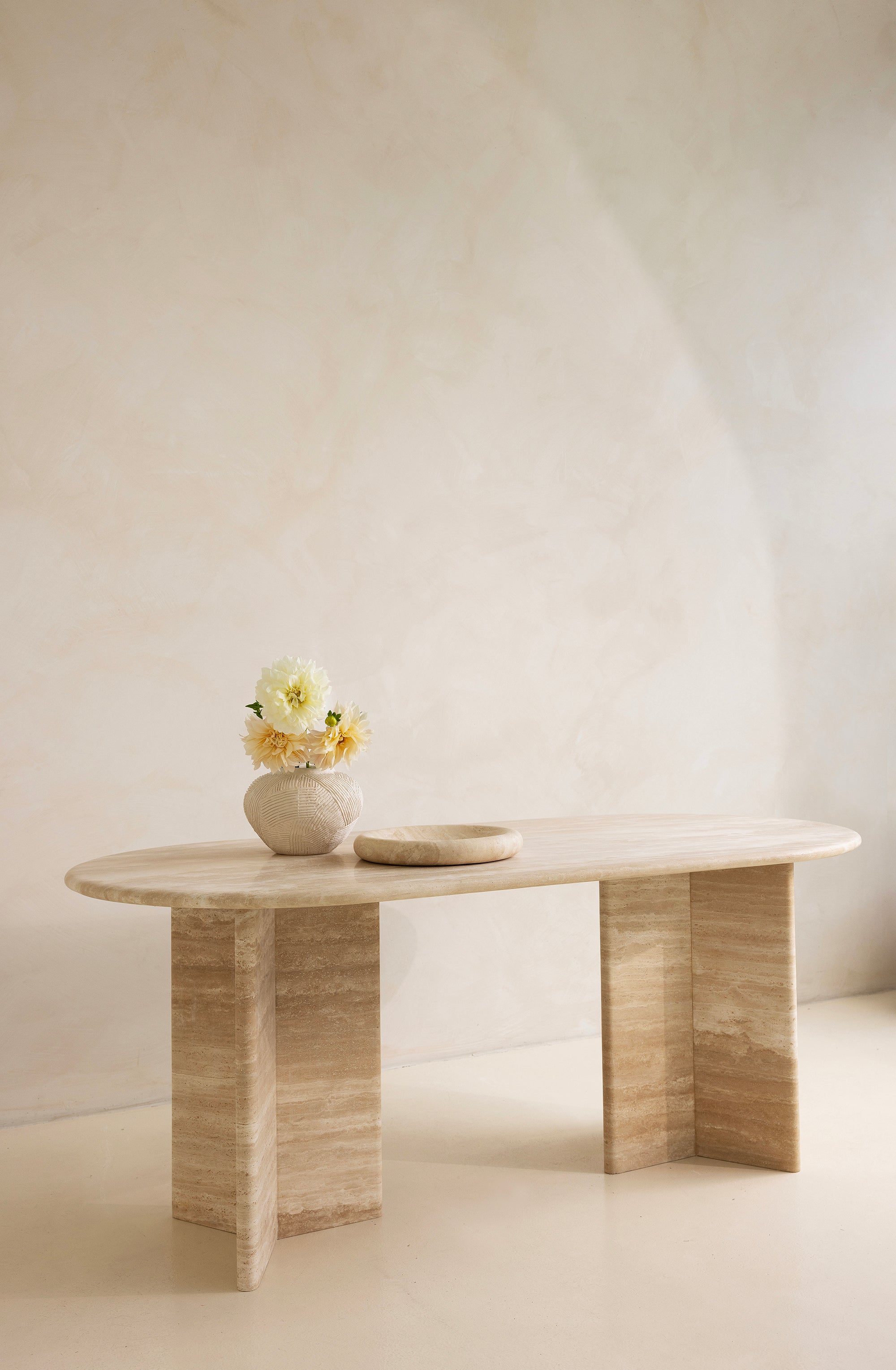 A rectangular dining table with curved edges, made of light-colored wood, displayed against a neutral background.