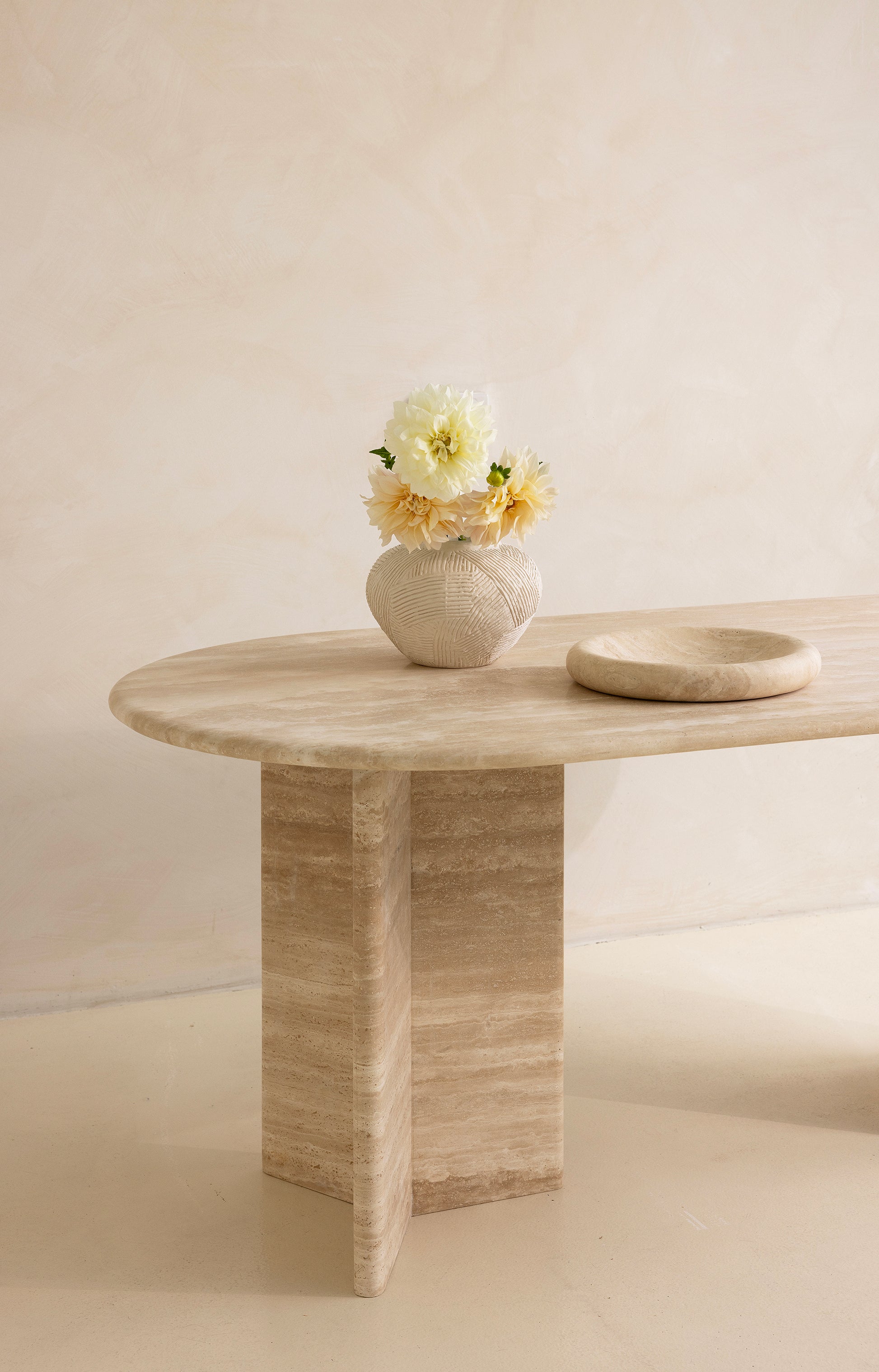A rectangular dining table with curved edges, made of light-colored wood, displayed against a neutral background.