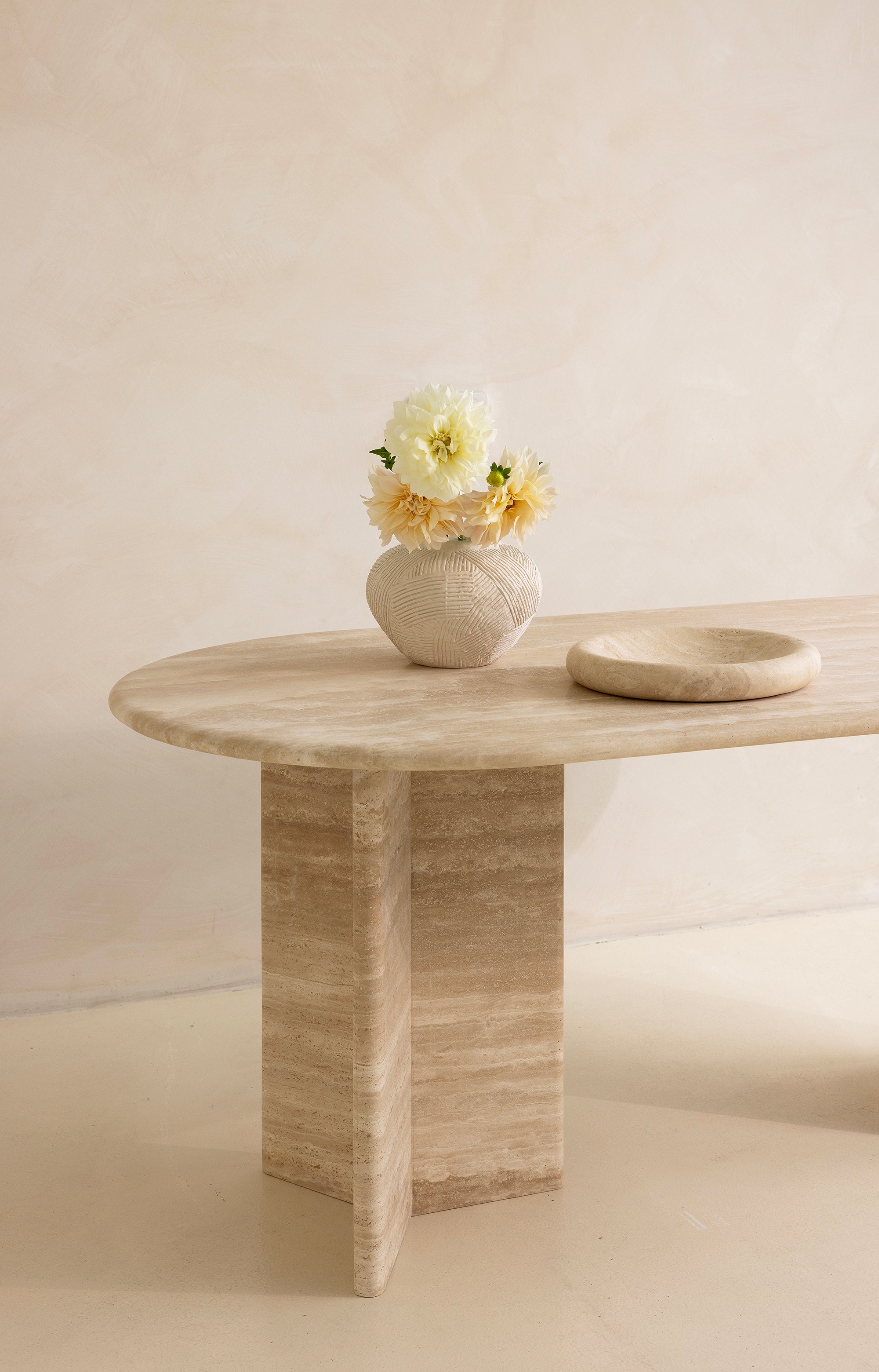A rectangular dining table with curved edges, made of light-colored wood, displayed against a neutral background.