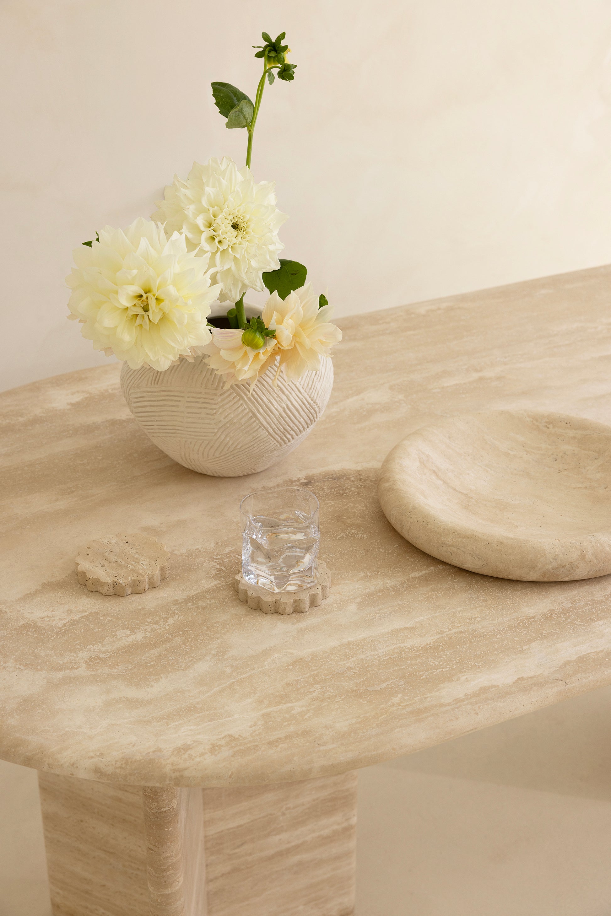 A rectangular dining table with curved edges, made of light-colored wood, displayed against a neutral background.
