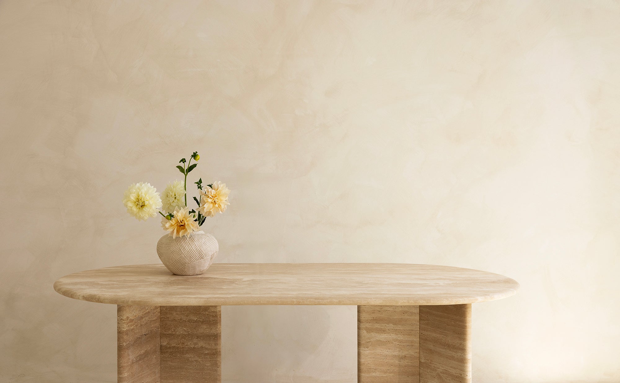 A rectangular dining table with curved edges, made of light-colored wood, displayed against a neutral background.