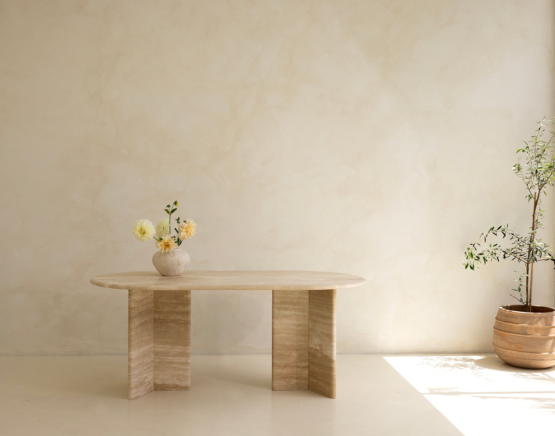 A rectangular dining table with curved edges, made of light-colored wood, displayed against a neutral background.