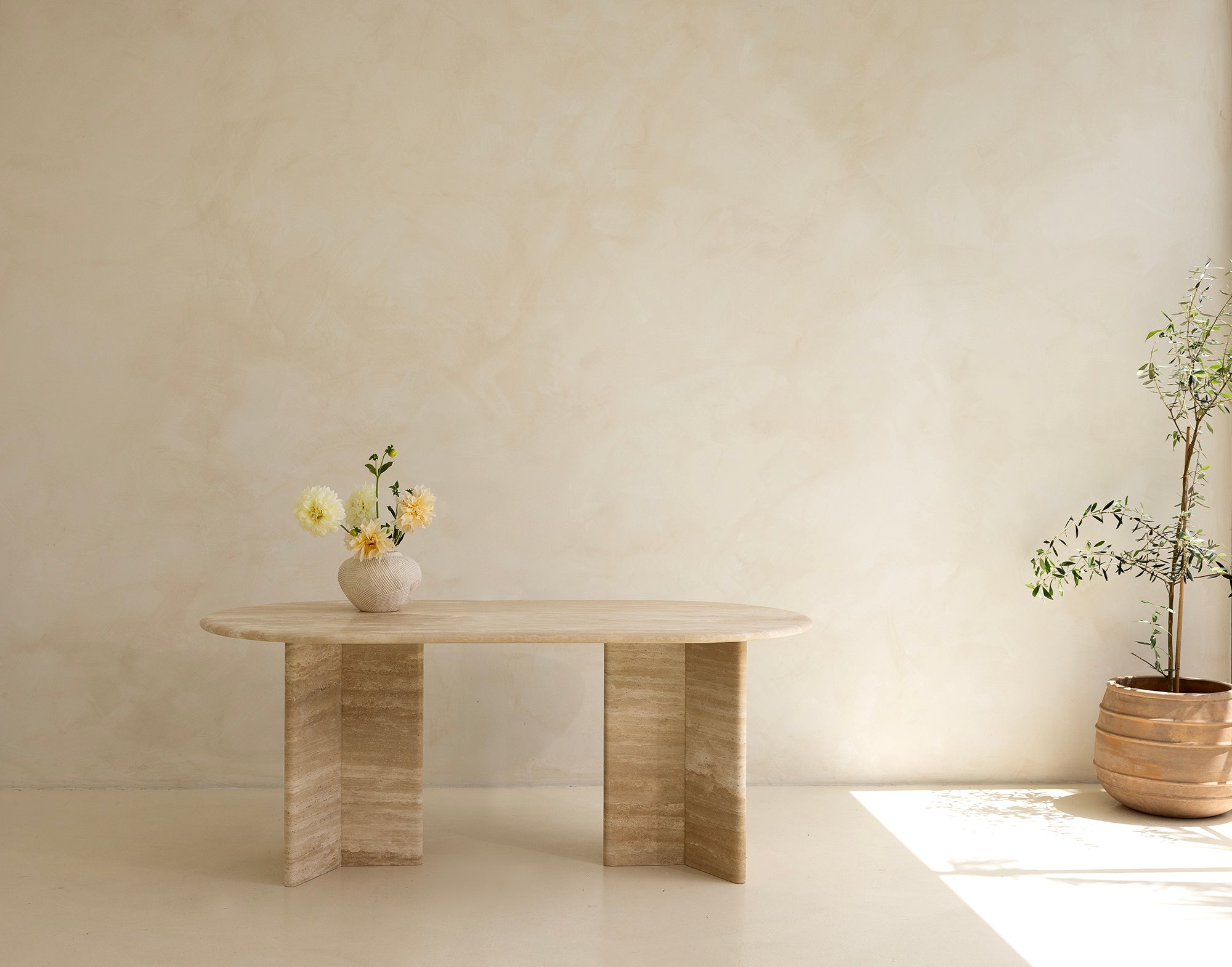 A rectangular dining table with curved edges, made of light-colored wood, displayed against a neutral background.