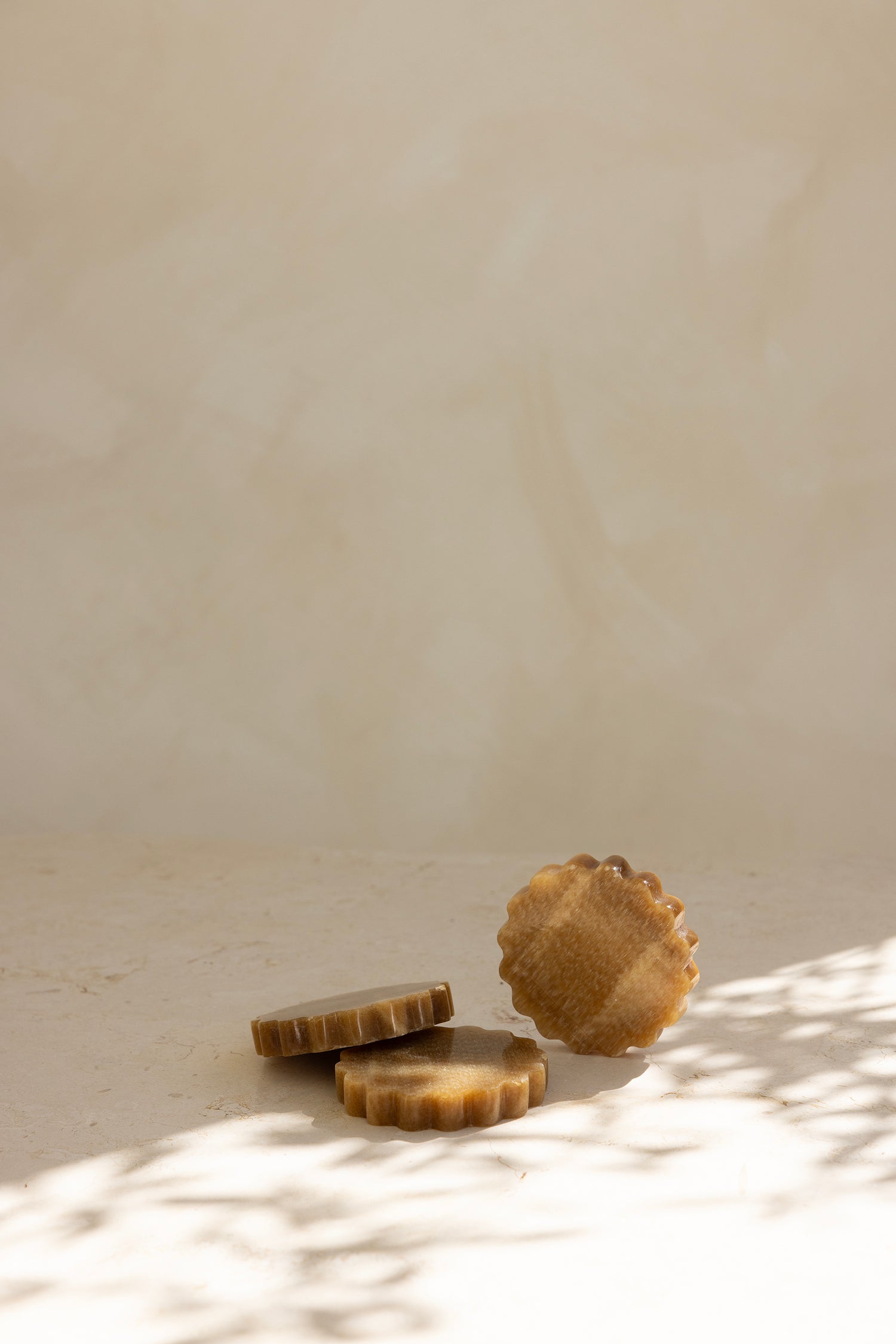 A round caramel onyx coaster with a wave pattern, displayed on a neutral background.