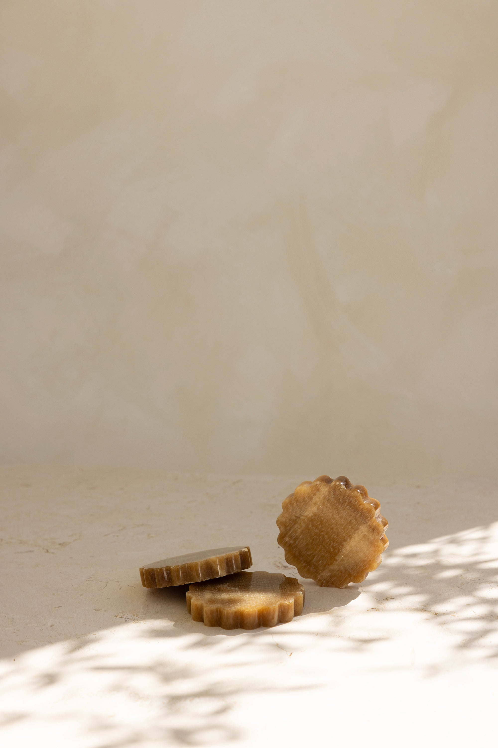 A round caramel onyx coaster with a wave pattern, displayed on a neutral background.