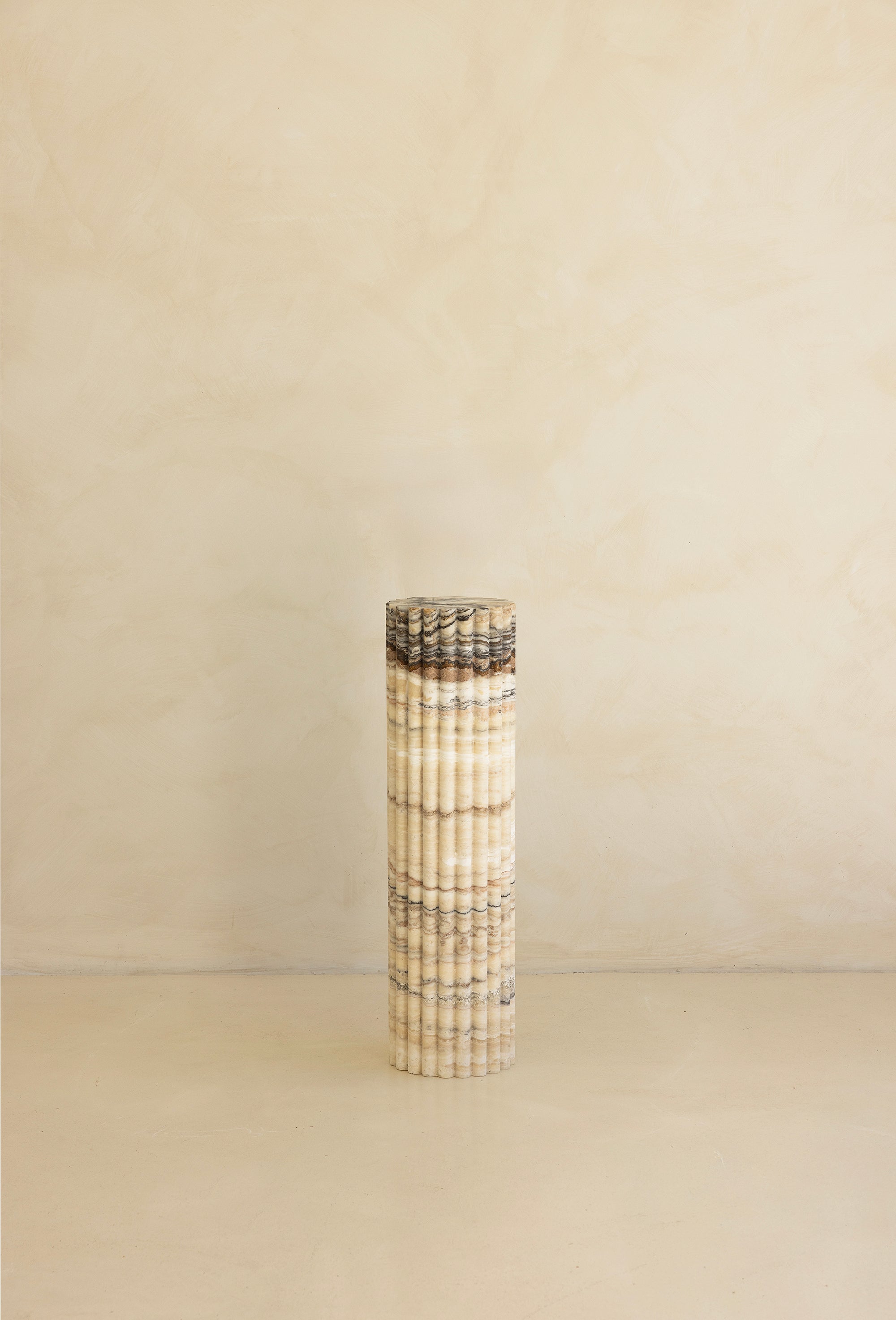 A beige travertine decorative tray with a wave pattern, displayed on a plain background.