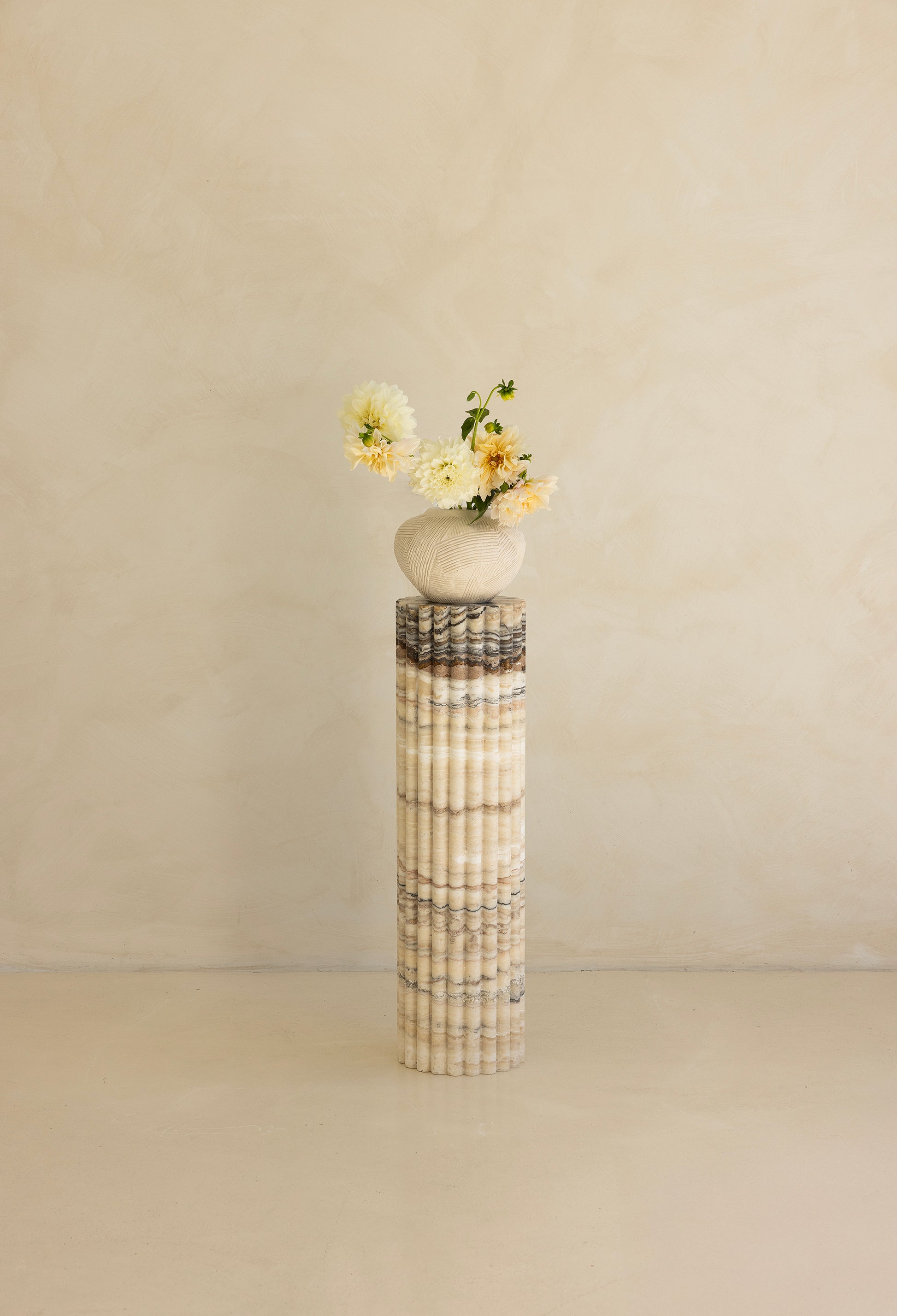 A beige travertine decorative tray with a wave pattern, displayed on a plain background.