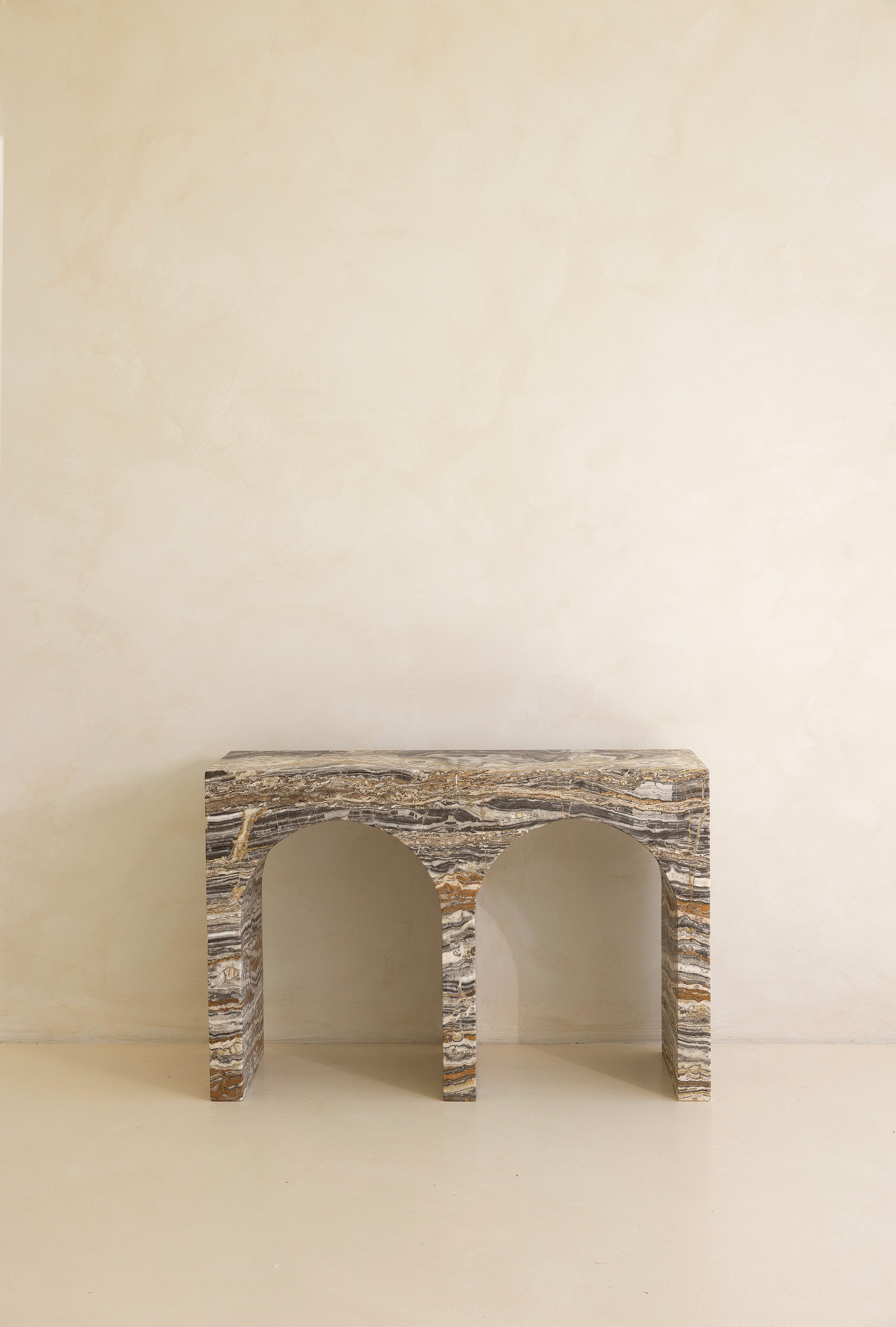 A marble console table with twin arches and a dramatic stone pattern against a neutral background.