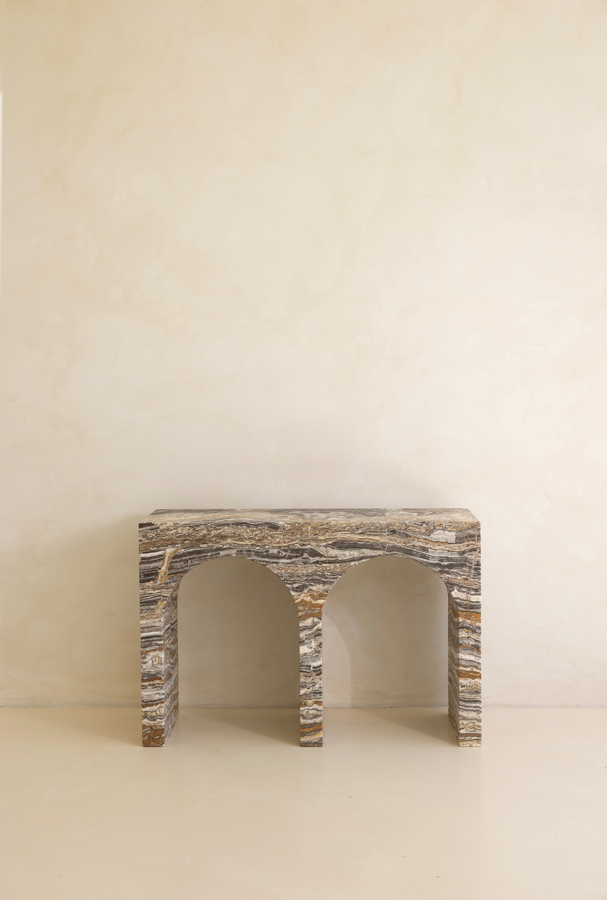 A marble console table with twin arches and a dramatic stone pattern against a neutral background.