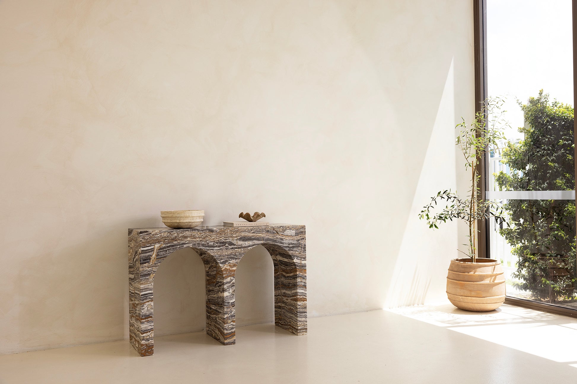 A marble console table with twin arches and a dramatic stone pattern against a neutral background.