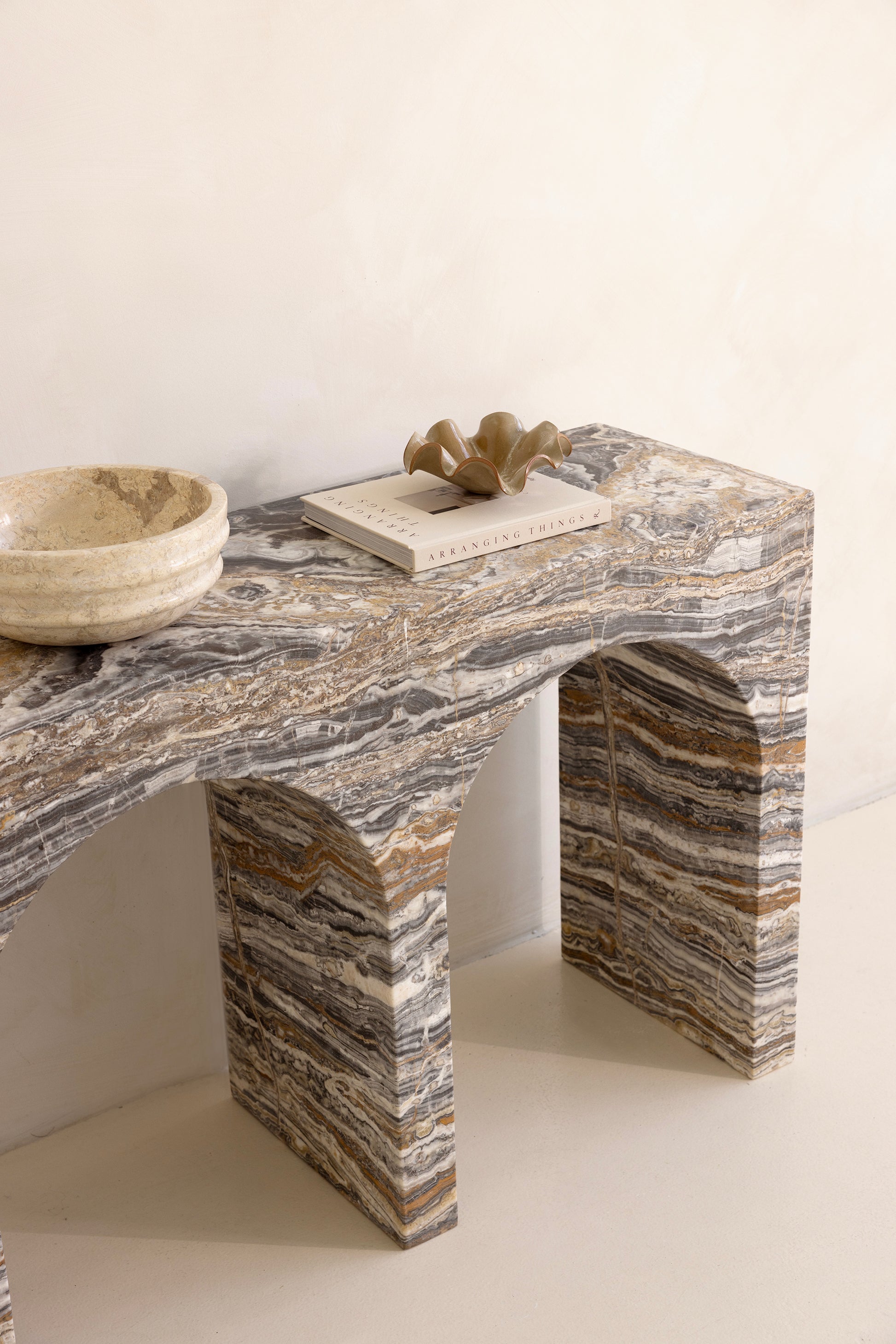 A marble console table with twin arches and a dramatic stone pattern against a neutral background.