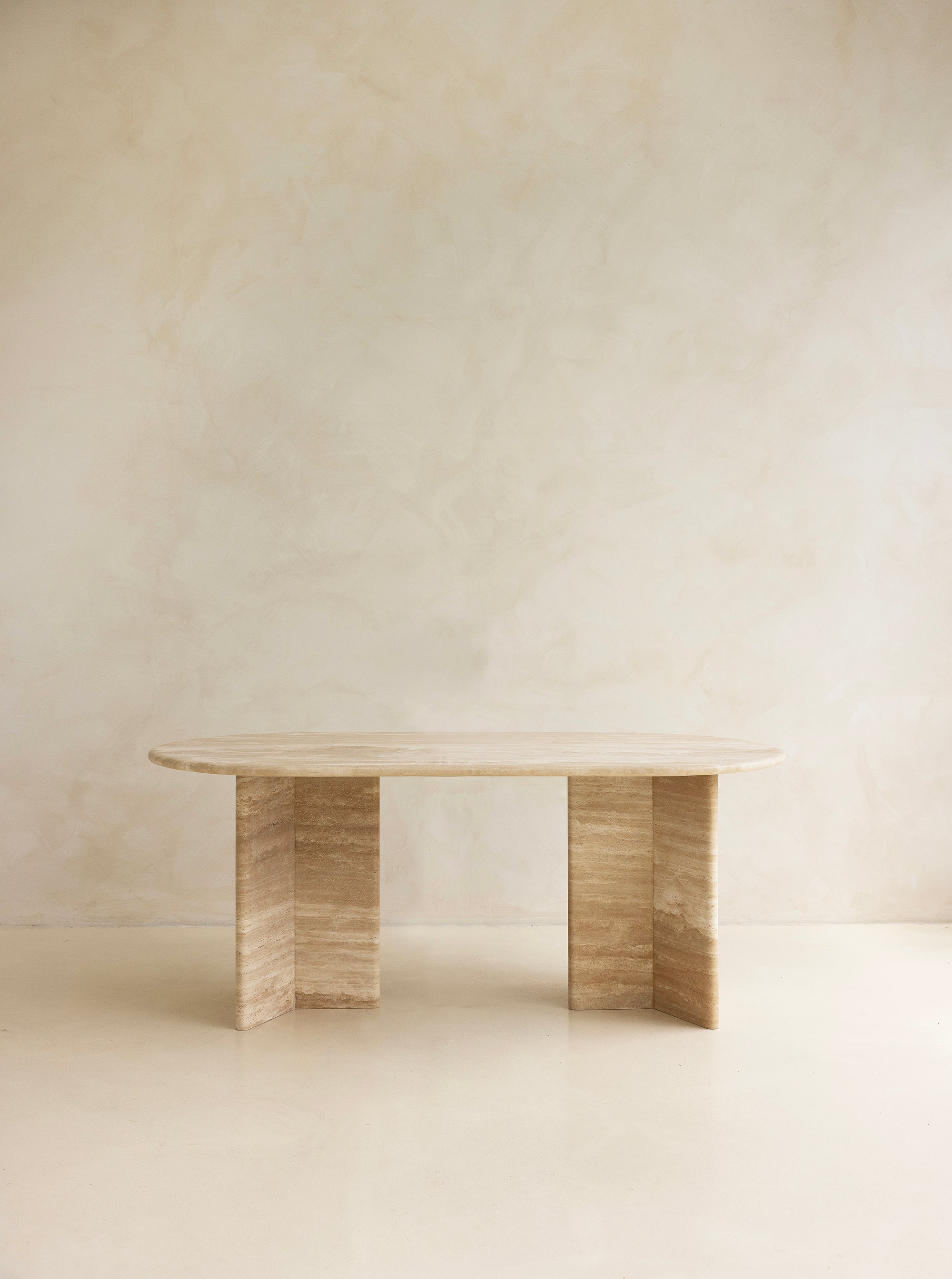 A rectangular dining table with curved edges, made of light-colored wood, displayed against a neutral background.